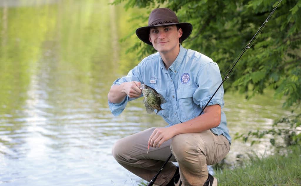 student shows off the fish he caught